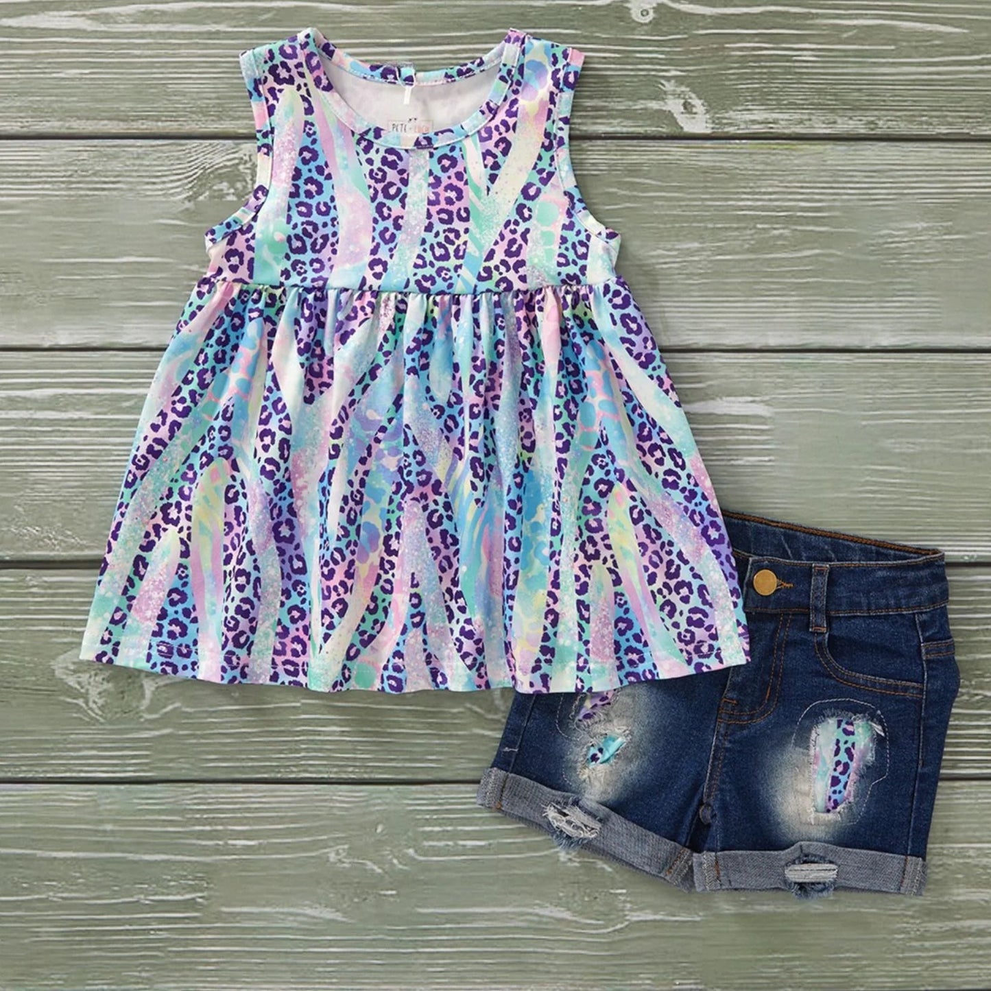 Multicolored leopard print dress and denim shorts on a wooden surface