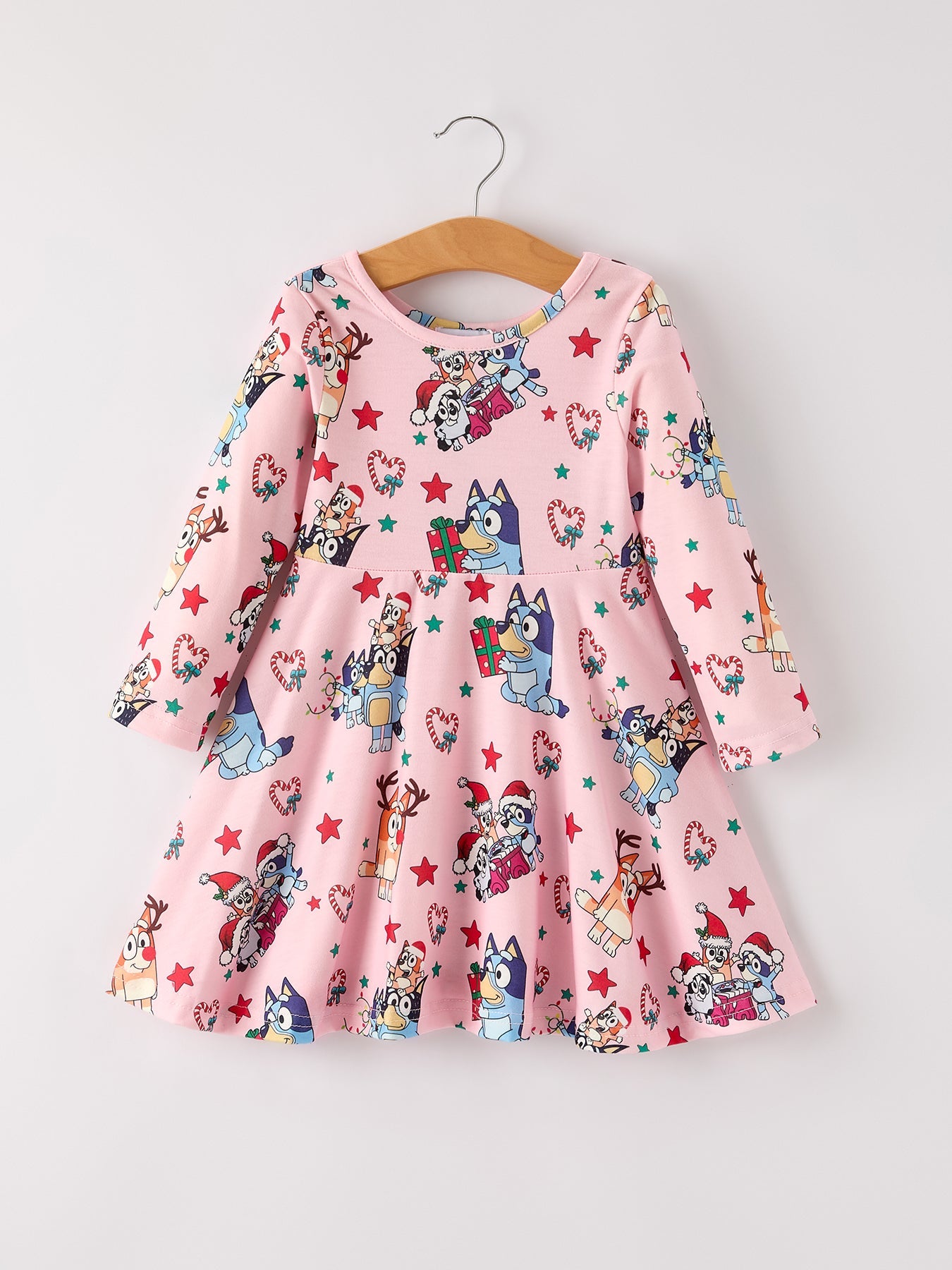 Pink dress with cartoon character print on a hanger against a white background