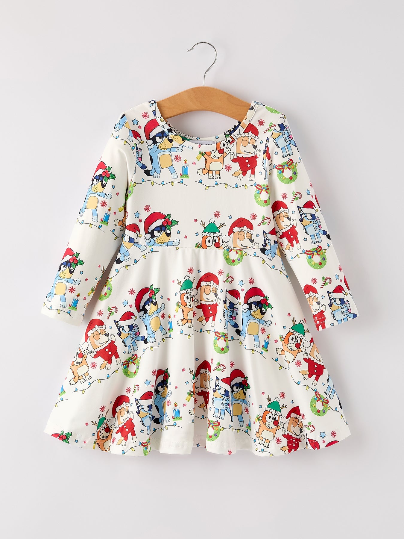 Children's dress with Christmas-themed print on a hanger against a white background