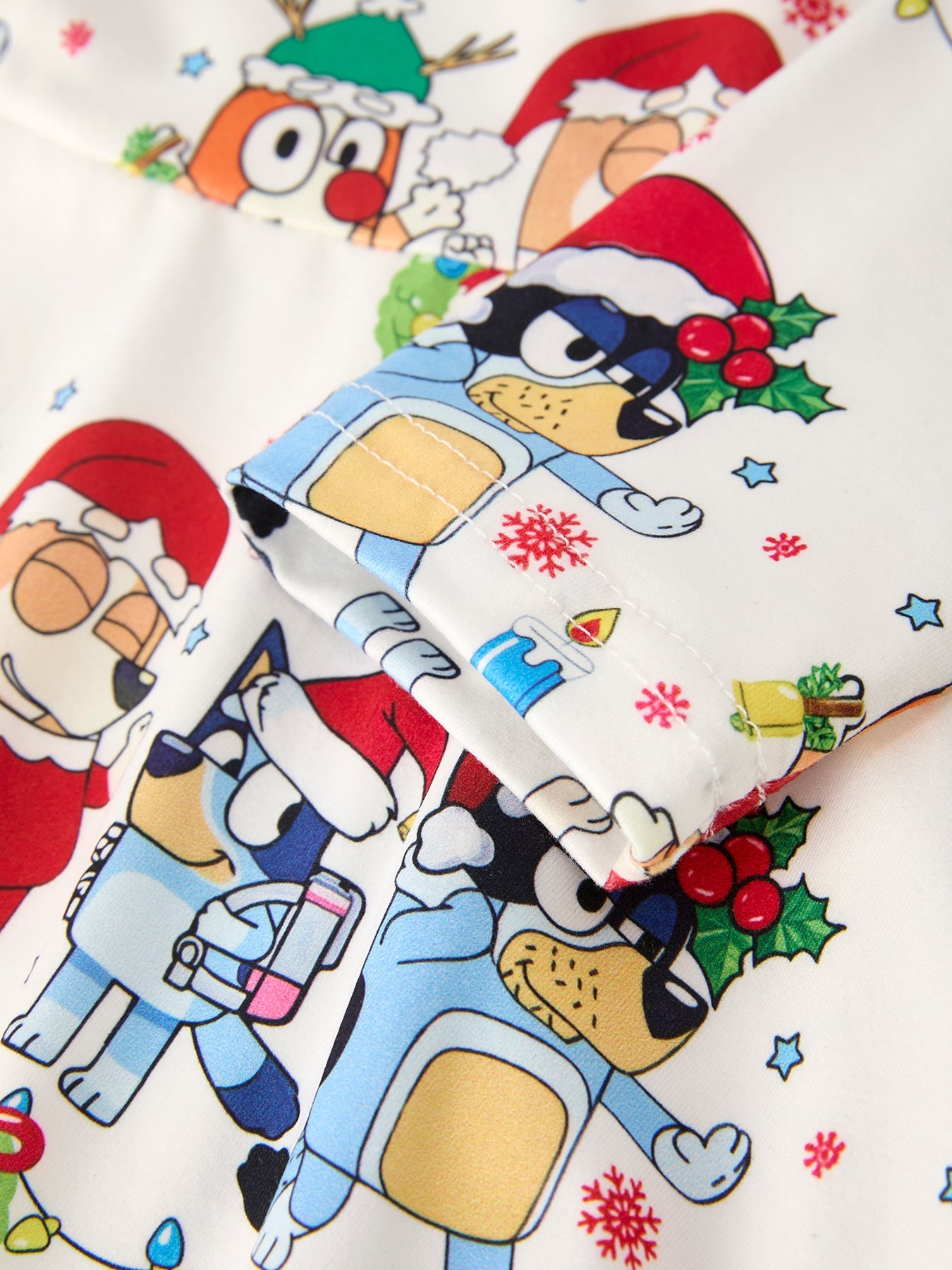 Christmas-themed fabric with cartoon characters wearing Santa hats and winter clothing.