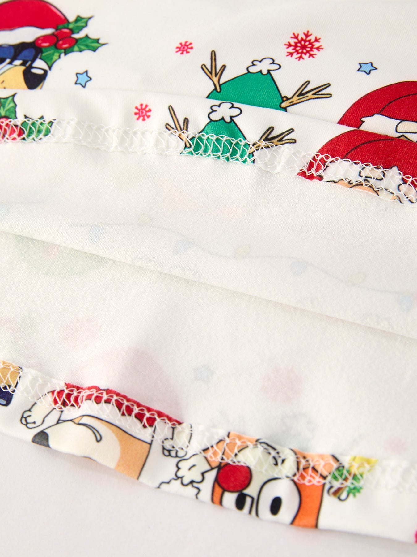 Christmas-themed fabric with cartoon characters and festive designs on a white background