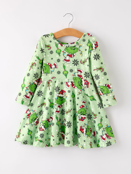 Green dress with festive pattern on a hanger against a white background
