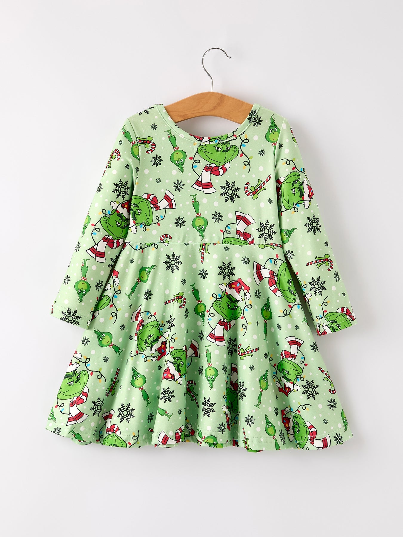 Green dress with Grinch pattern on a hanger against a white background