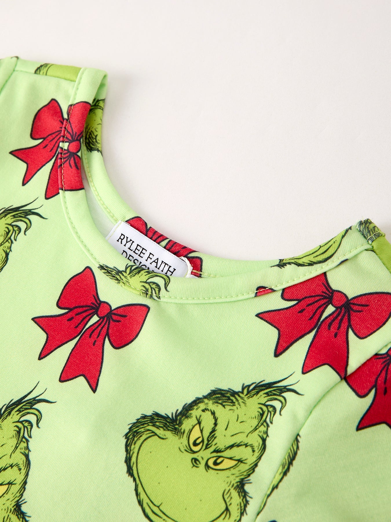 Green garment with red bows and Grinch faces on a white background