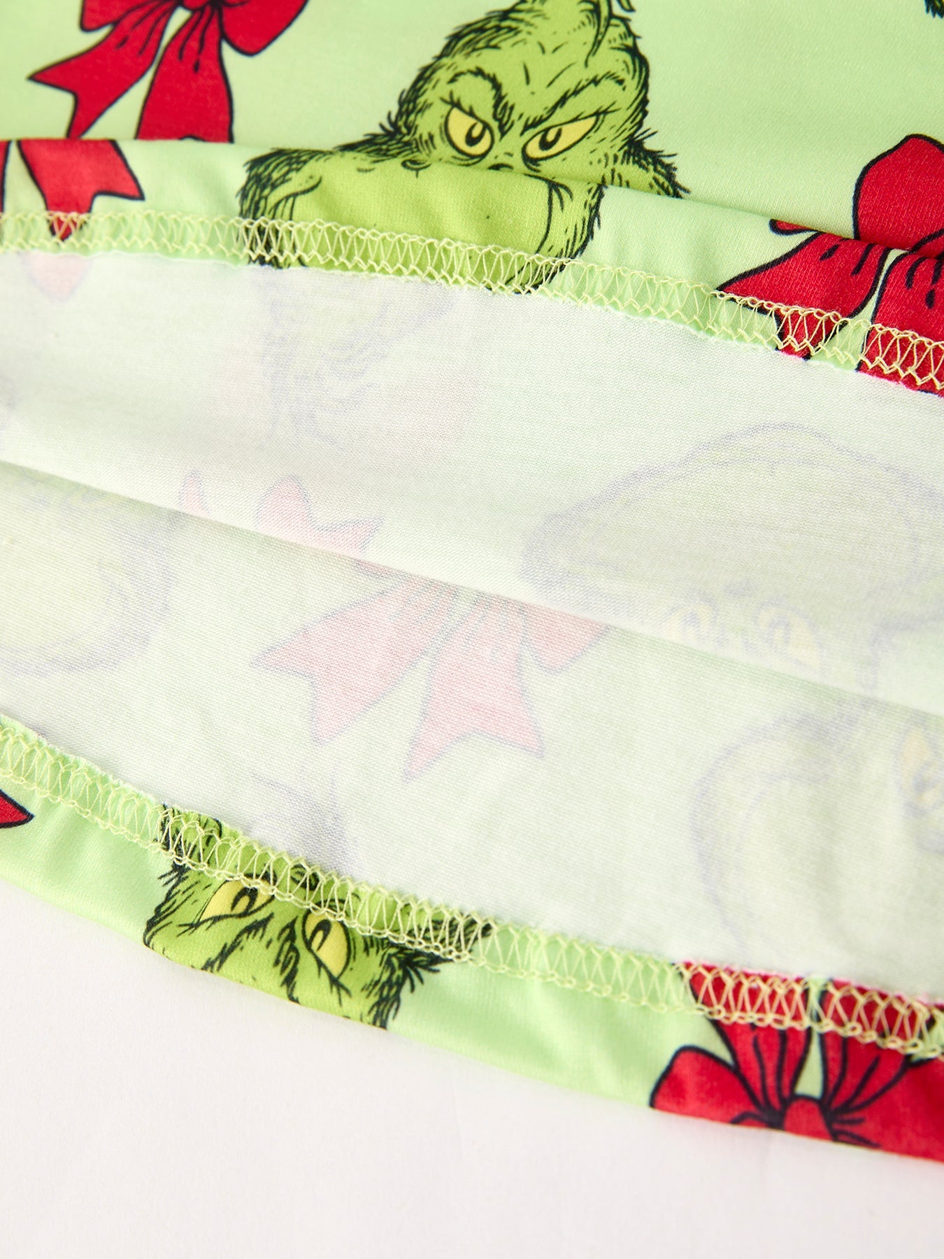 Close-up of a patterned fabric strip with a character design and red bows.