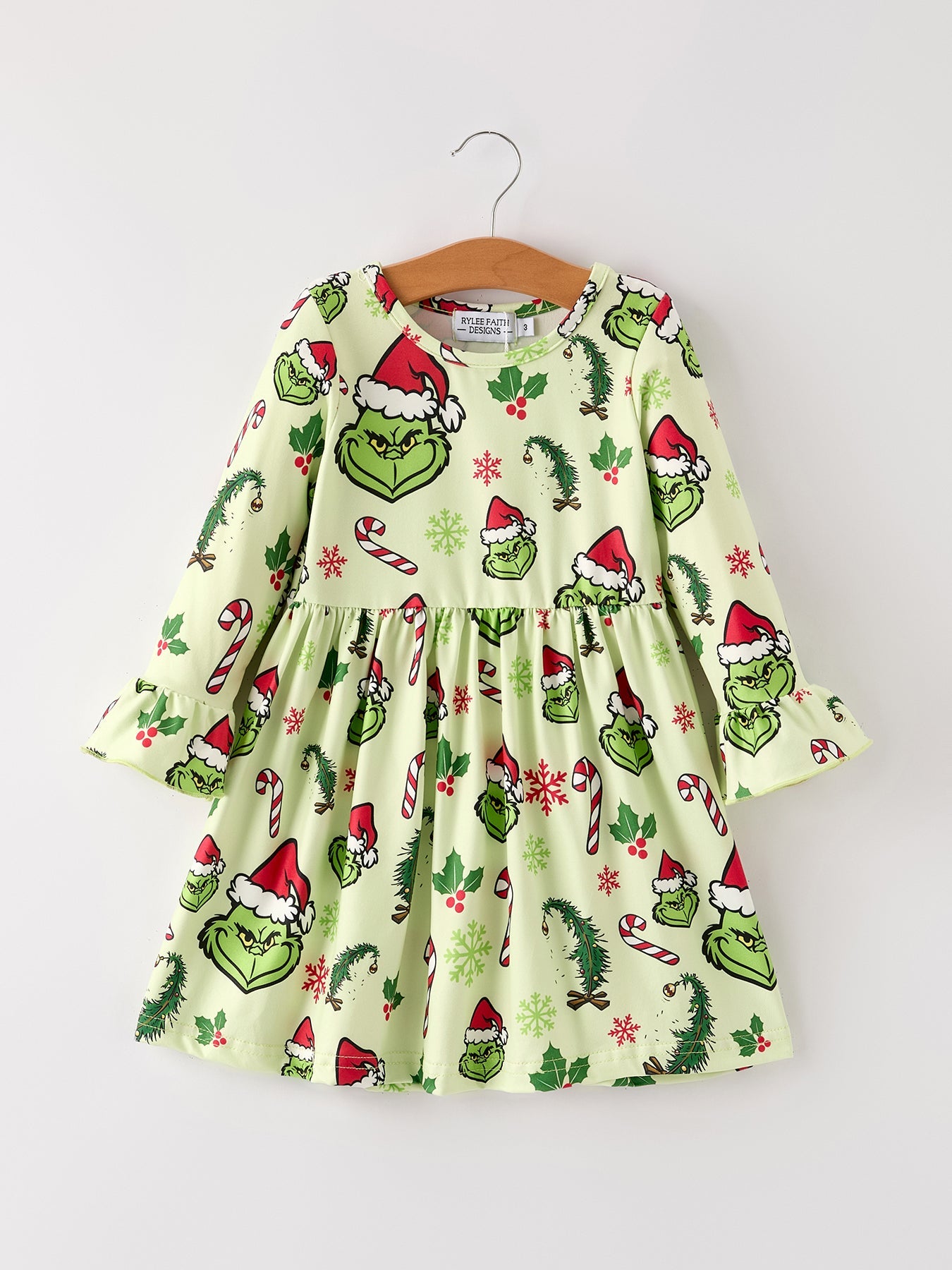 Children's dress with Grinch pattern on a hanger against a white background