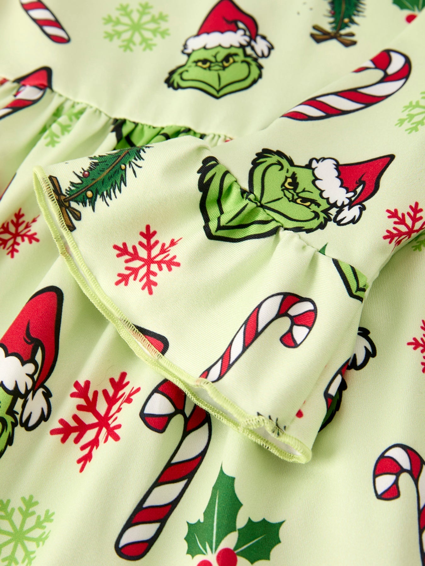 Christmas-themed fabric with Grinch characters, candy canes, and snowflakes on a light green background.
