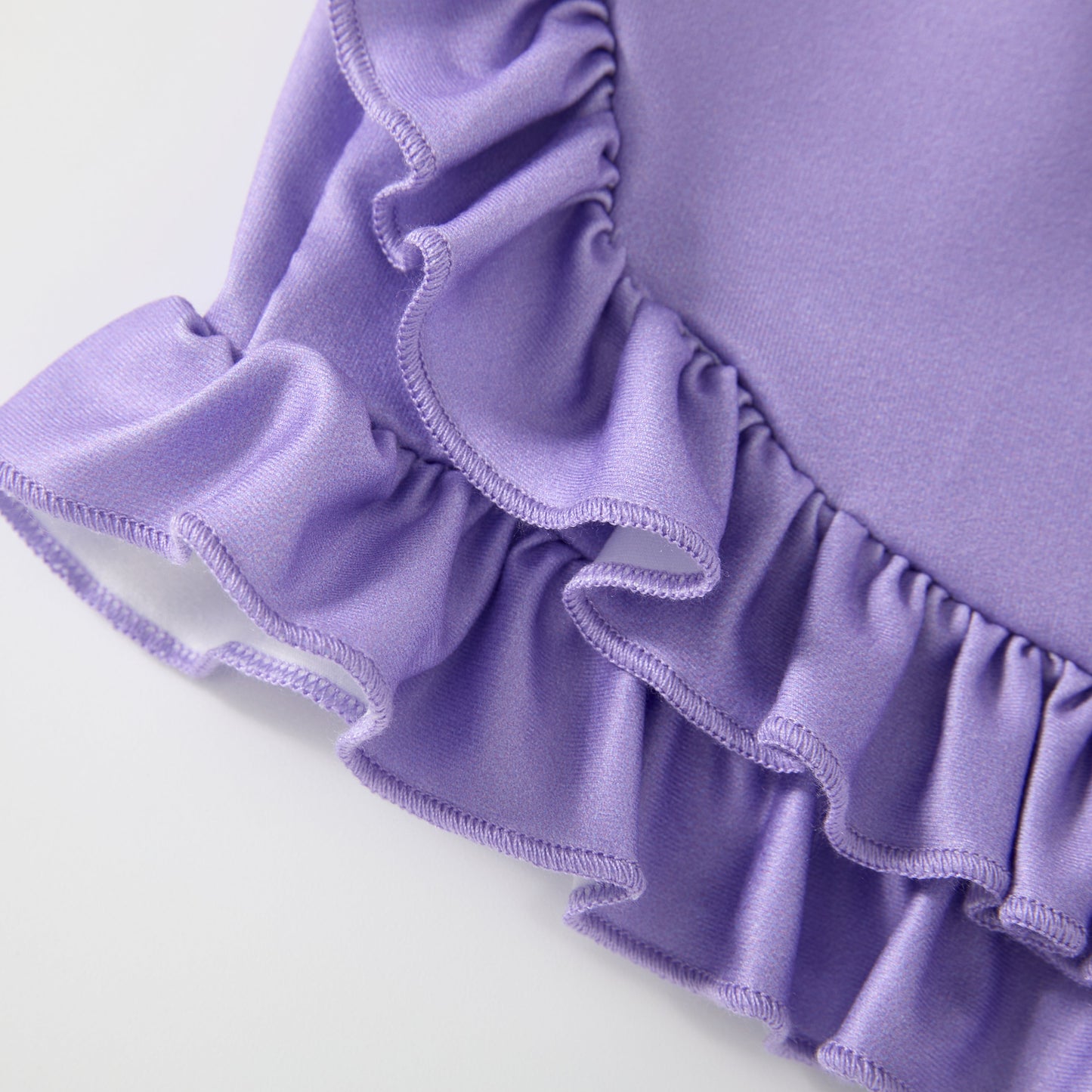 Close-up of a purple fabric with ruffled edges on a white background