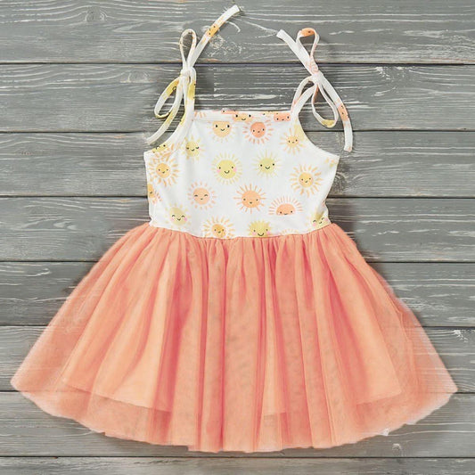 Children's dress with floral top and pink skirt on a wooden background