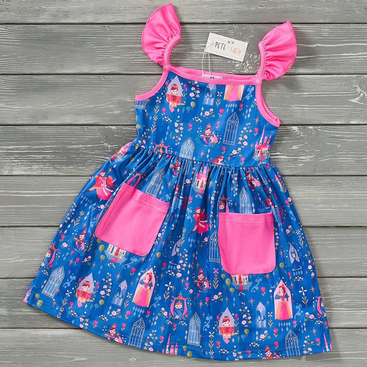 A blue dress with dream-themed graphics such as castles and stars, featuring pink accents and a wooden texture background.