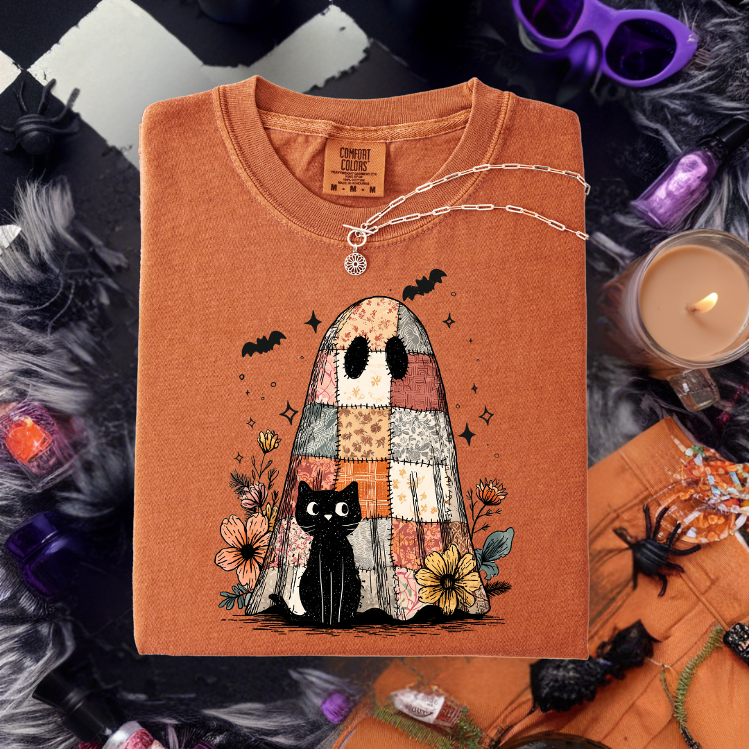 Orange t-shirt with a ghost and black cat design on a Halloween-themed background.