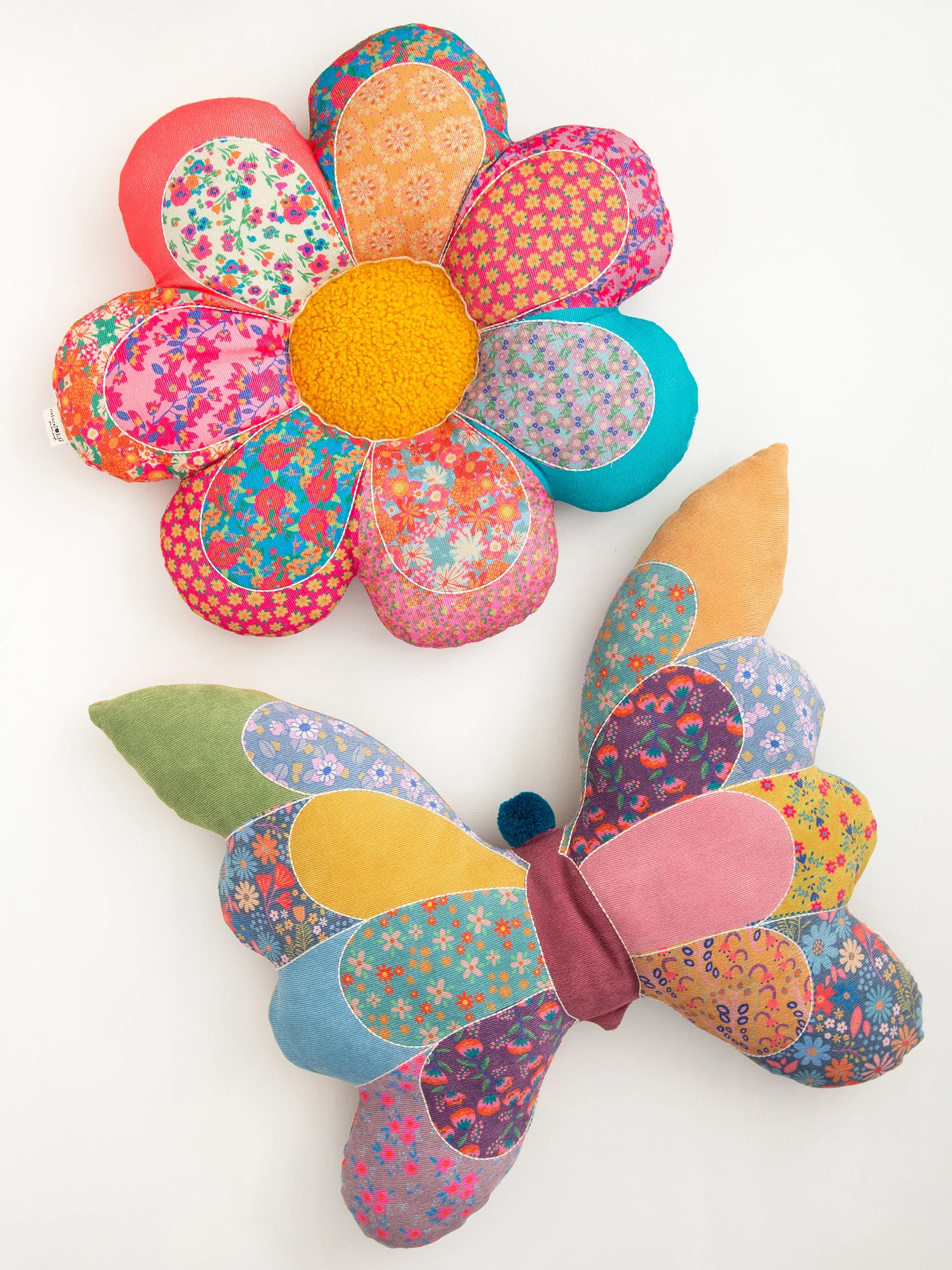 Colorful butterfly and flower-shaped cushions on a white background