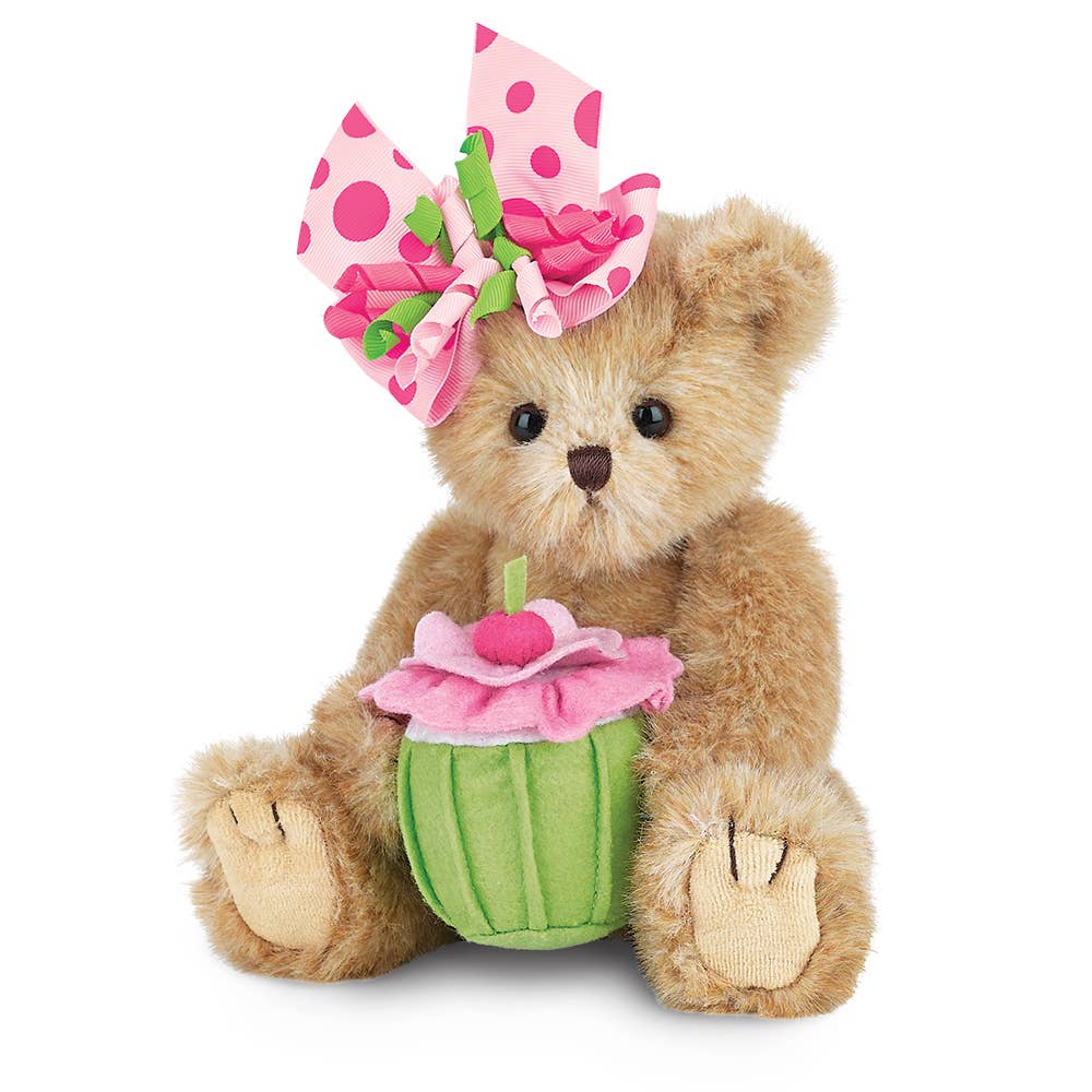 Teddy bear with a pink cupcake and flower accessory on a white background