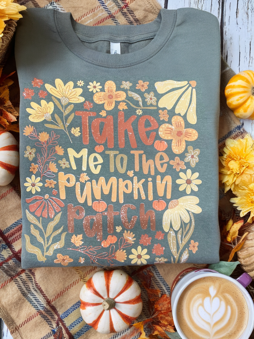 Sweatshirt with 'Take me to the pumpkin patch' design on a fall-themed background with pumpkins and leaves.