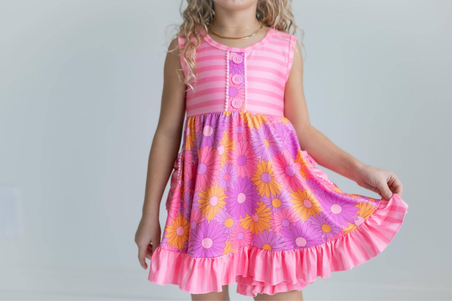 Child wearing a pink dress with floral patterns on a plain background