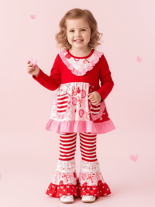 Child wearing a red and white outfit with hearts on a pink background