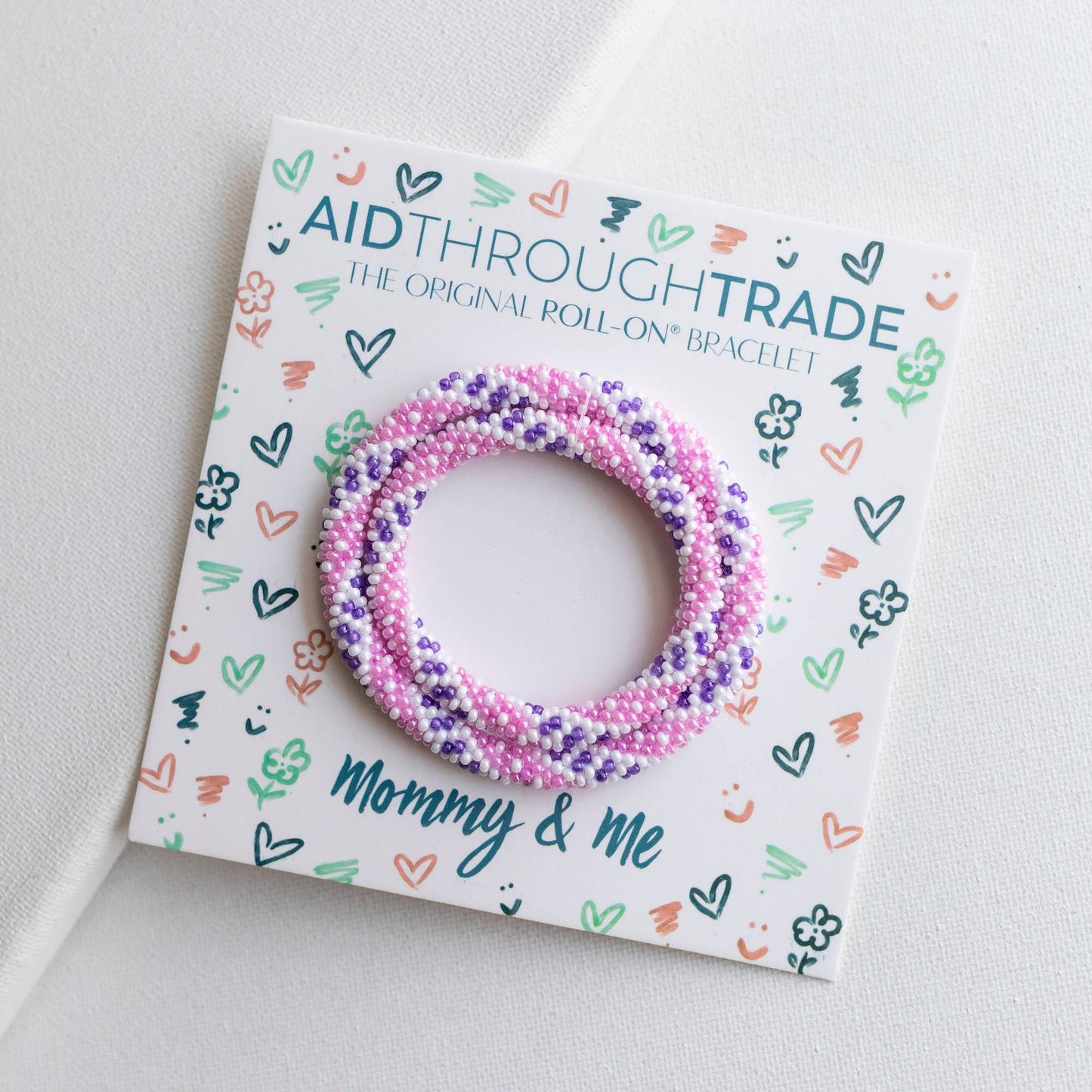 Colorful beaded bracelets on a 'Aid Through Trade' branded card with 'Mommy & Me' text.