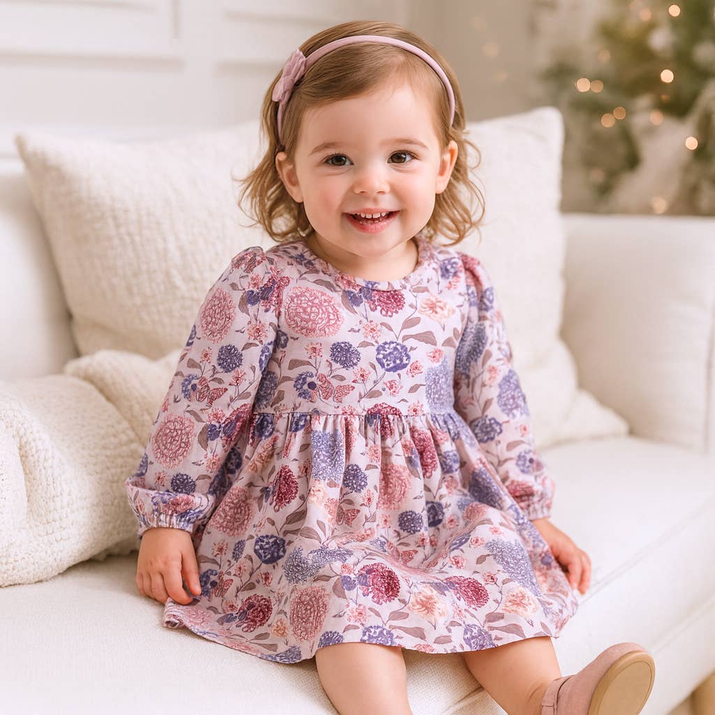 Child wearing a floral dress sitting on a white couch with a blurred background