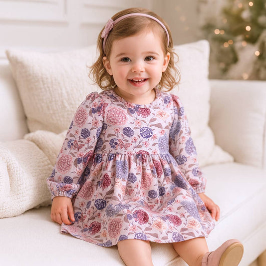 Child wearing a floral dress sitting on a white couch with a blurred background