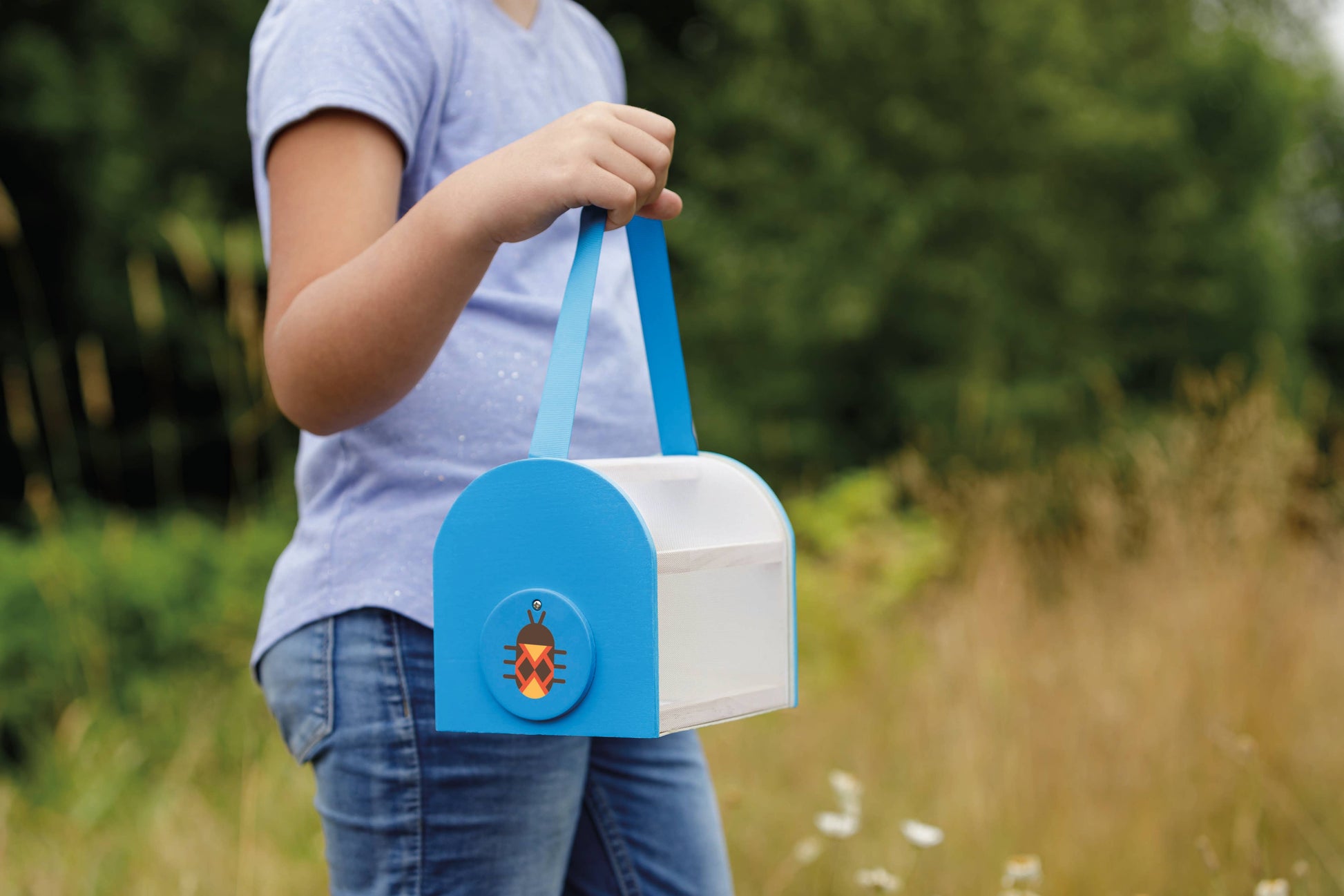 Person holding a blue and white box with a bug design outdoors