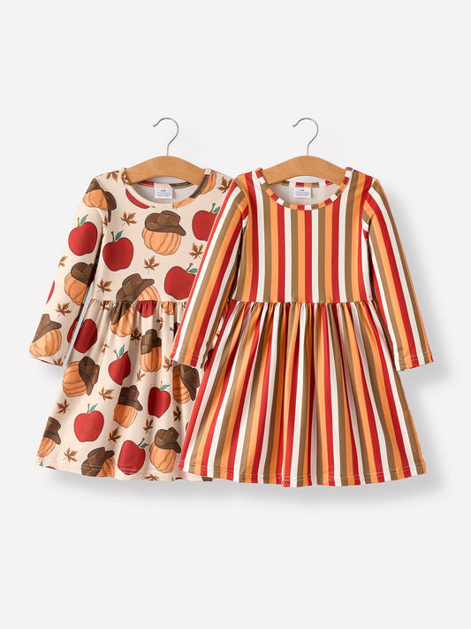 Two children's dresses on hangers with one having a pumpkin and apple pattern and the other in stripes.