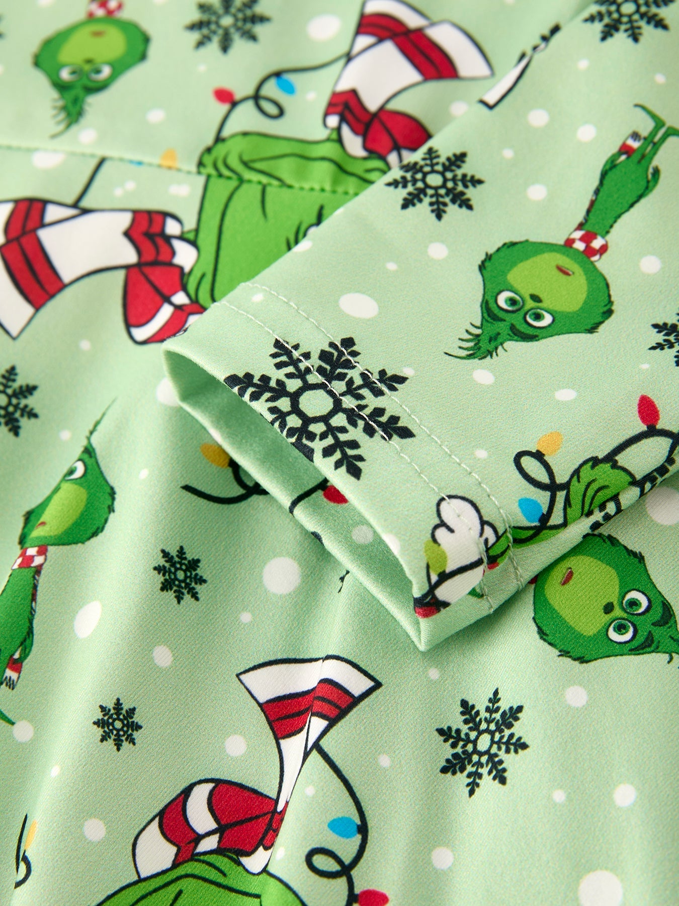 Christmas-themed fabric with Grinch characters and snowflakes on a green background