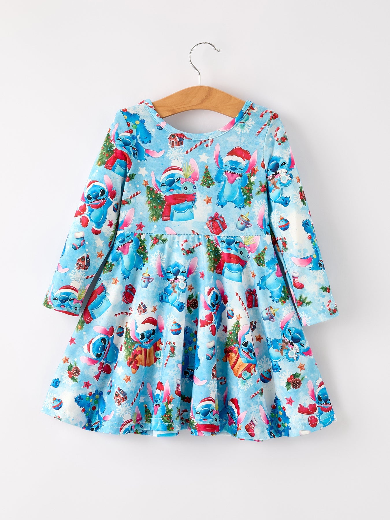 Children's dress with Christmas-themed design on a hanger against a white background