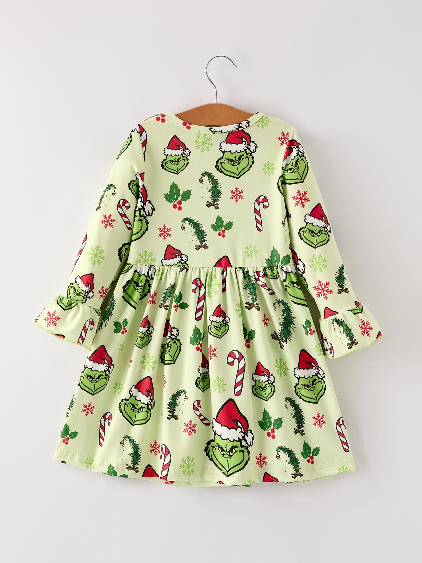 Children's dress with Grinch print on a hanger against a white background