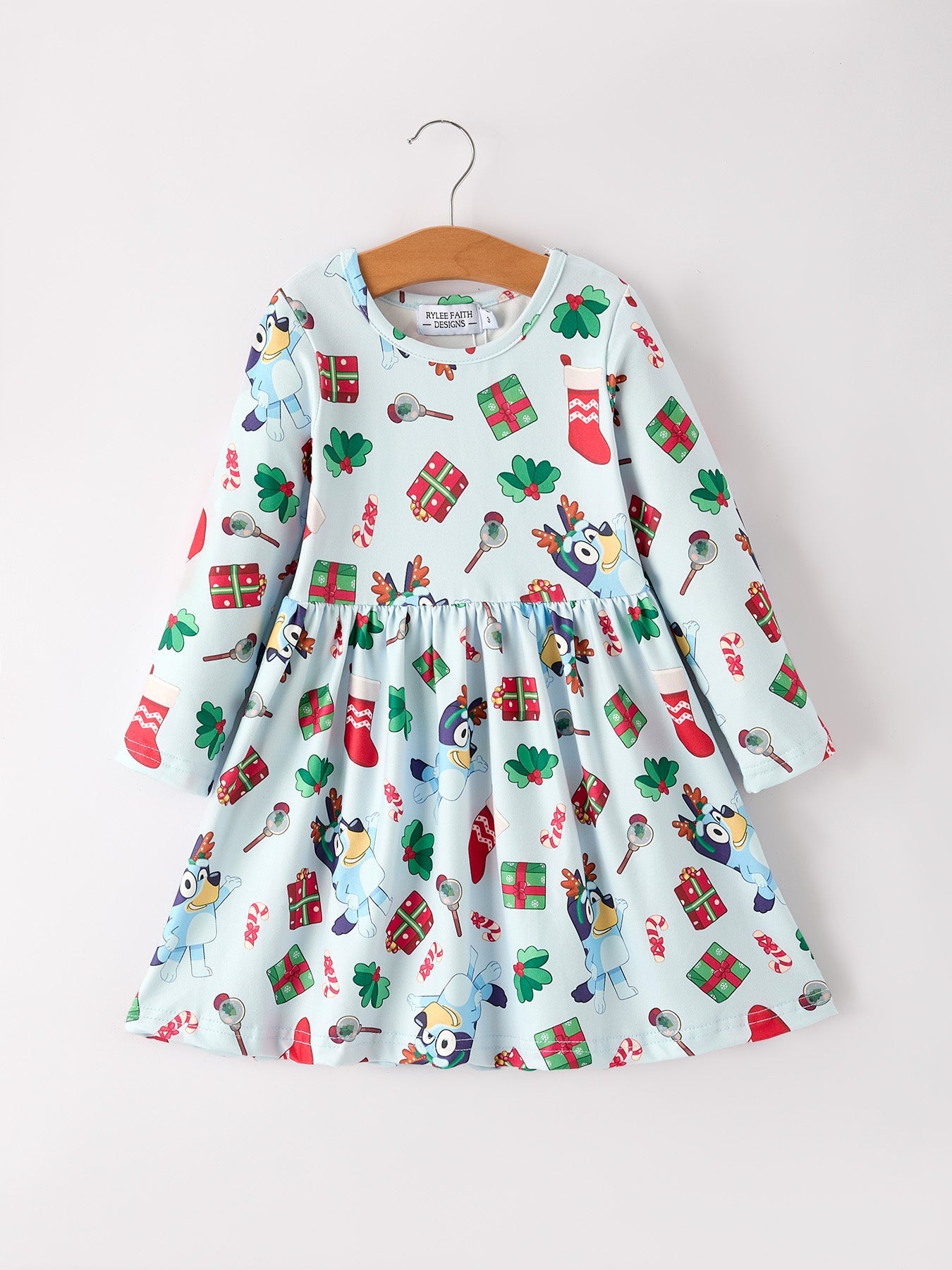 Children's dress with Christmas-themed pattern on a hanger against a white background