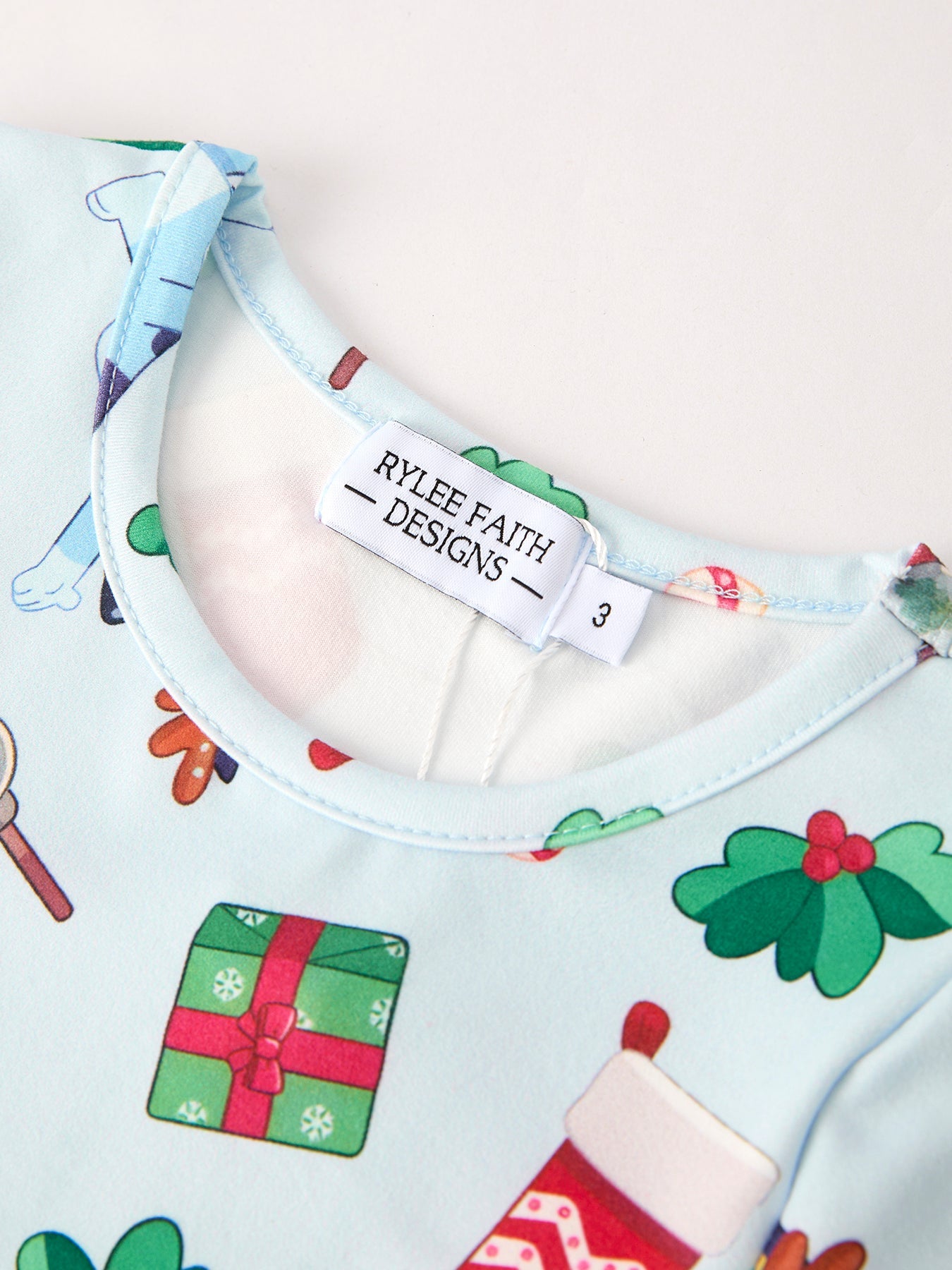 Baby bib with Christmas-themed design and 'Rylee Faith Designs' label.
