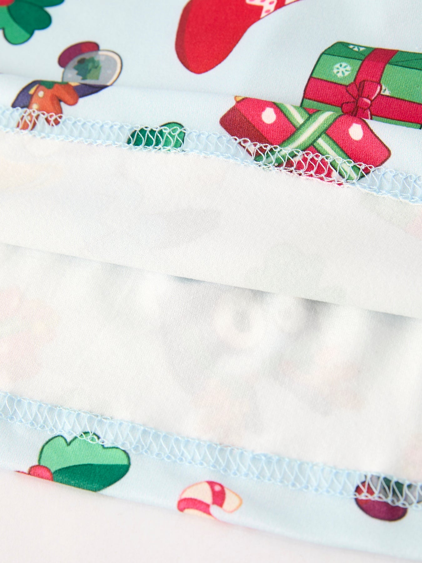 Close-up of a fabric with Christmas-themed designs including presents and trees on a white background.
