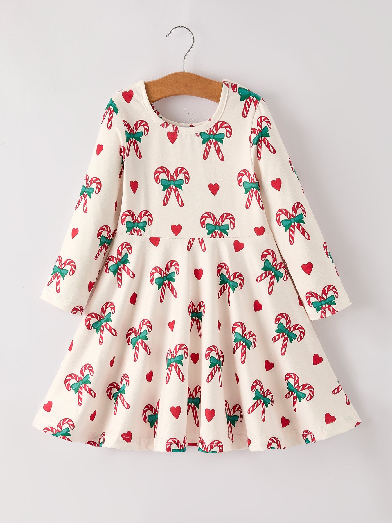 Children's dress with candy cane and bow pattern on a hanger against a white background