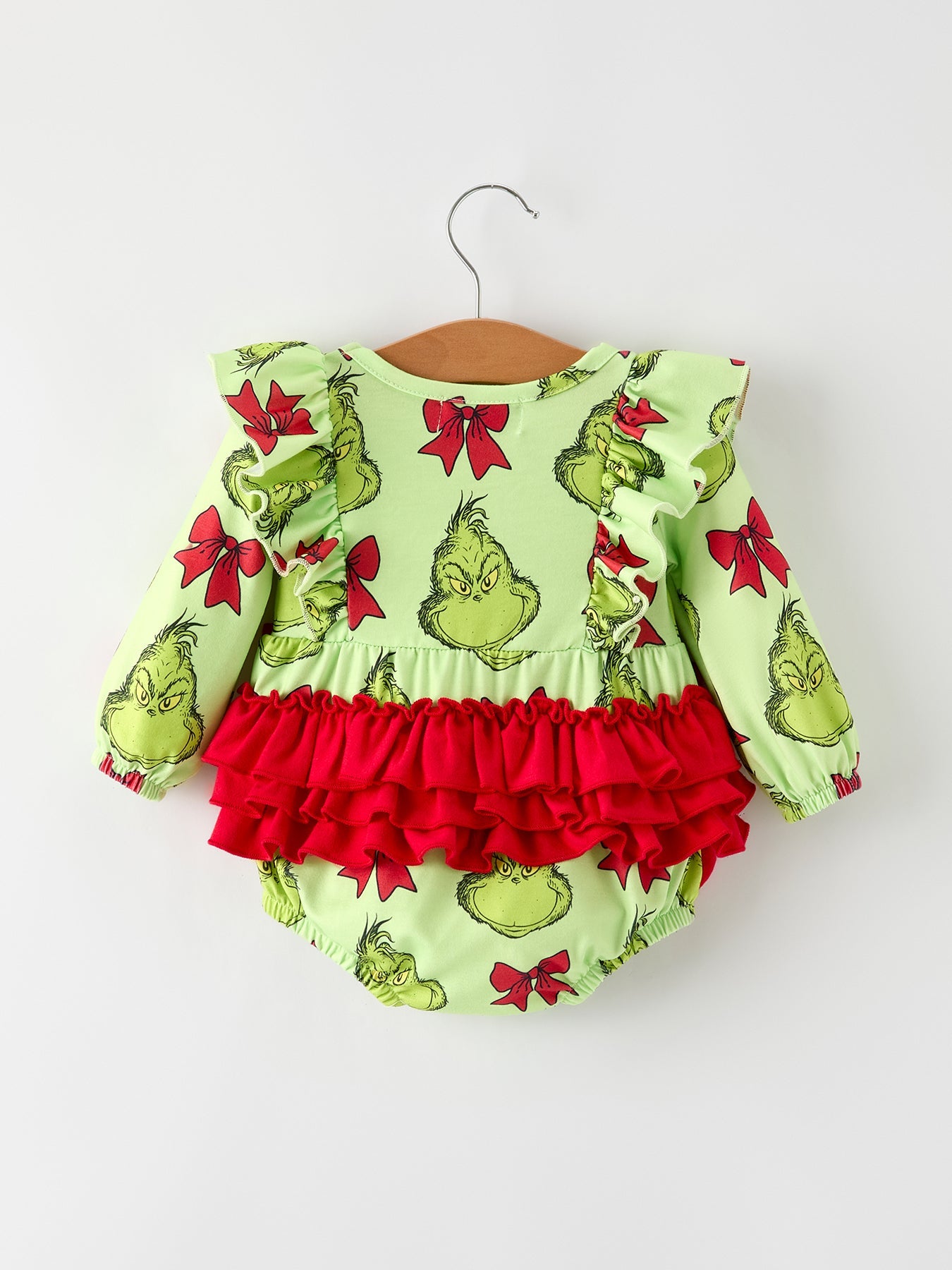 Baby romper with Grinch print on a hanger against a white background