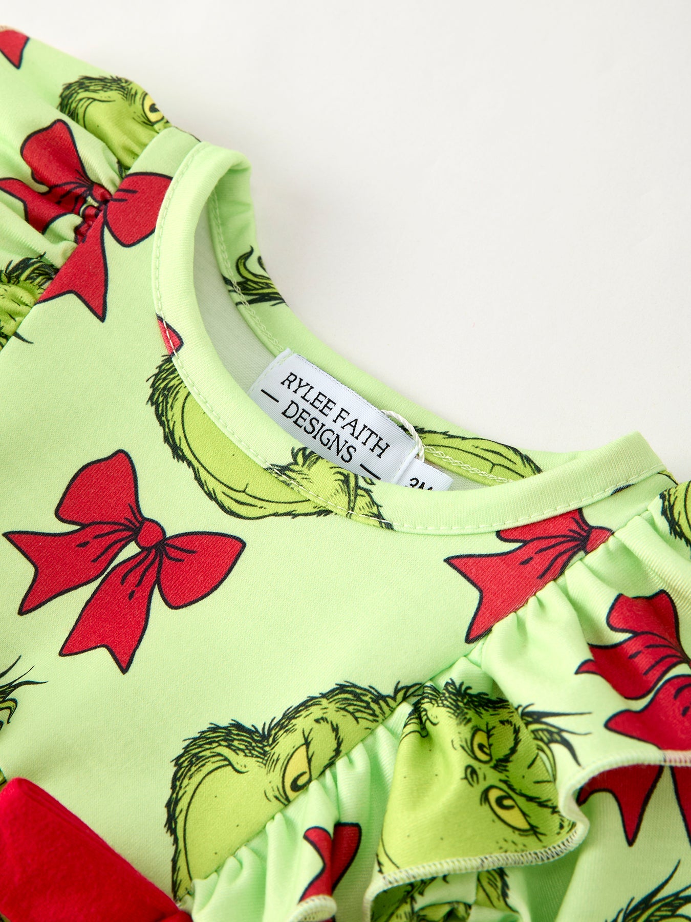 Children's outfit with Grinch design and red bows on a white background