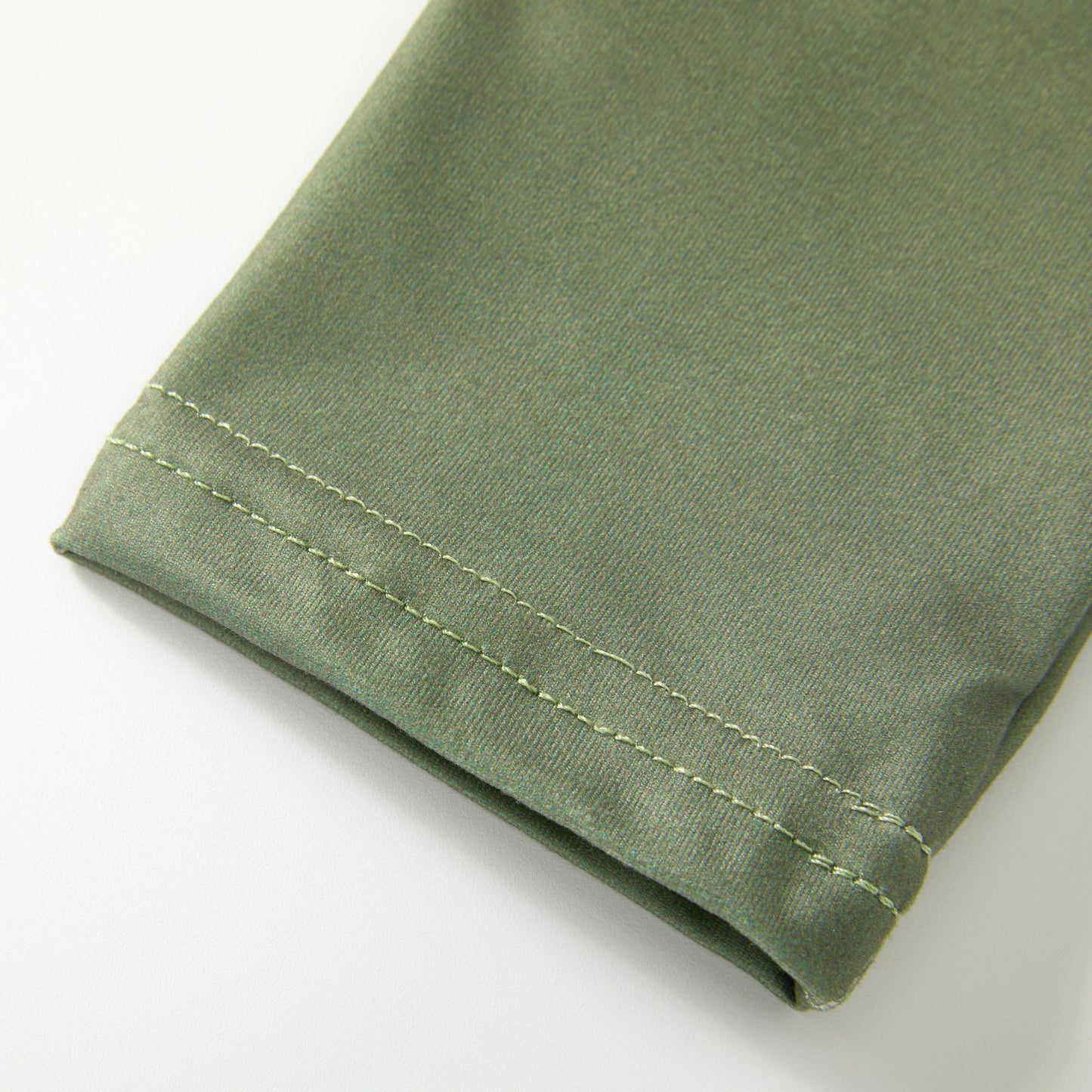 Close-up of a green fabric with a visible seam on a white background