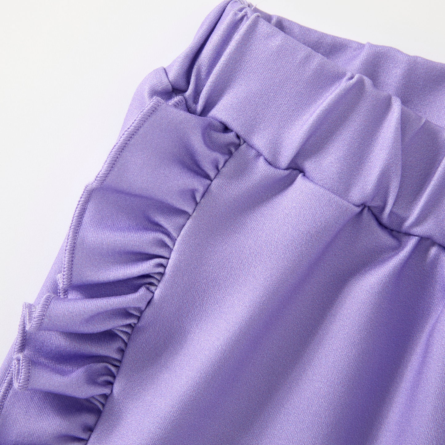 Close-up of a purple fabric with ruffled details on a light purple background