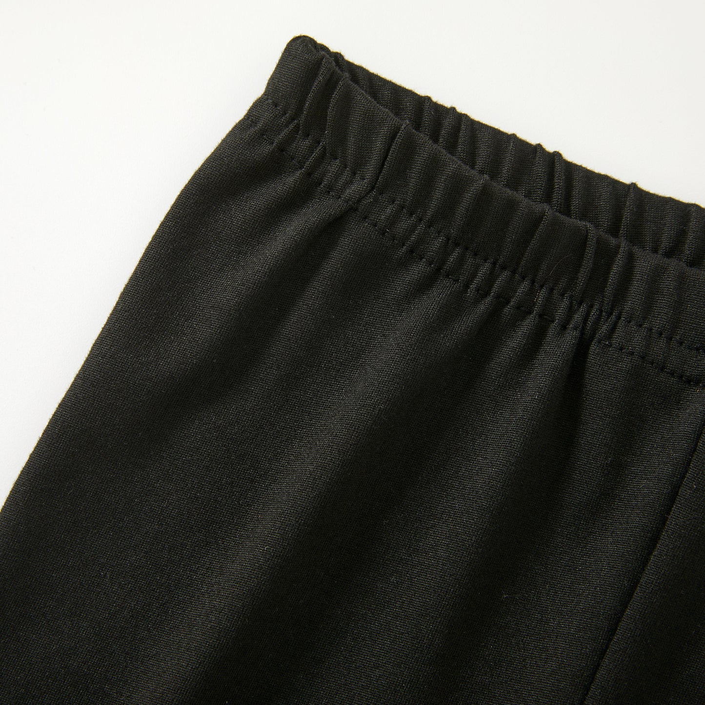 Close-up of the black elastic-waist pants on a plain white background.