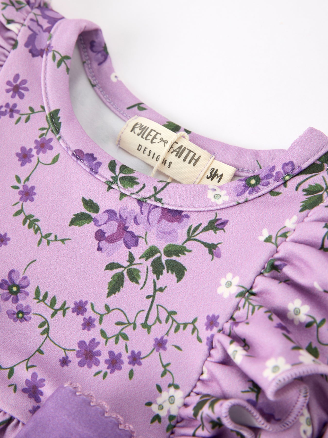 Purple floral baby dress with a visible brand label on a white background