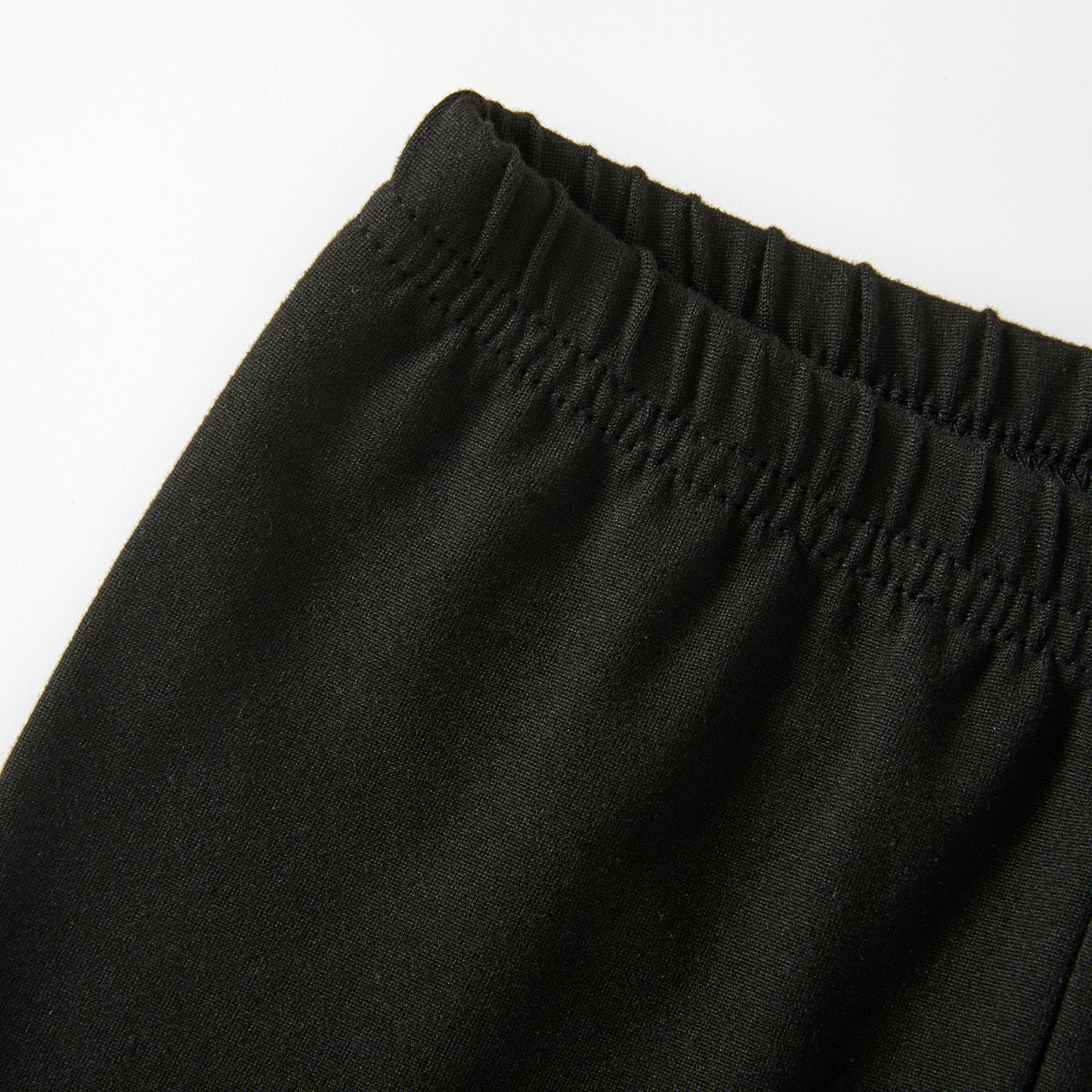 Close-up of the elastic waistband on the pants against a plain white background.