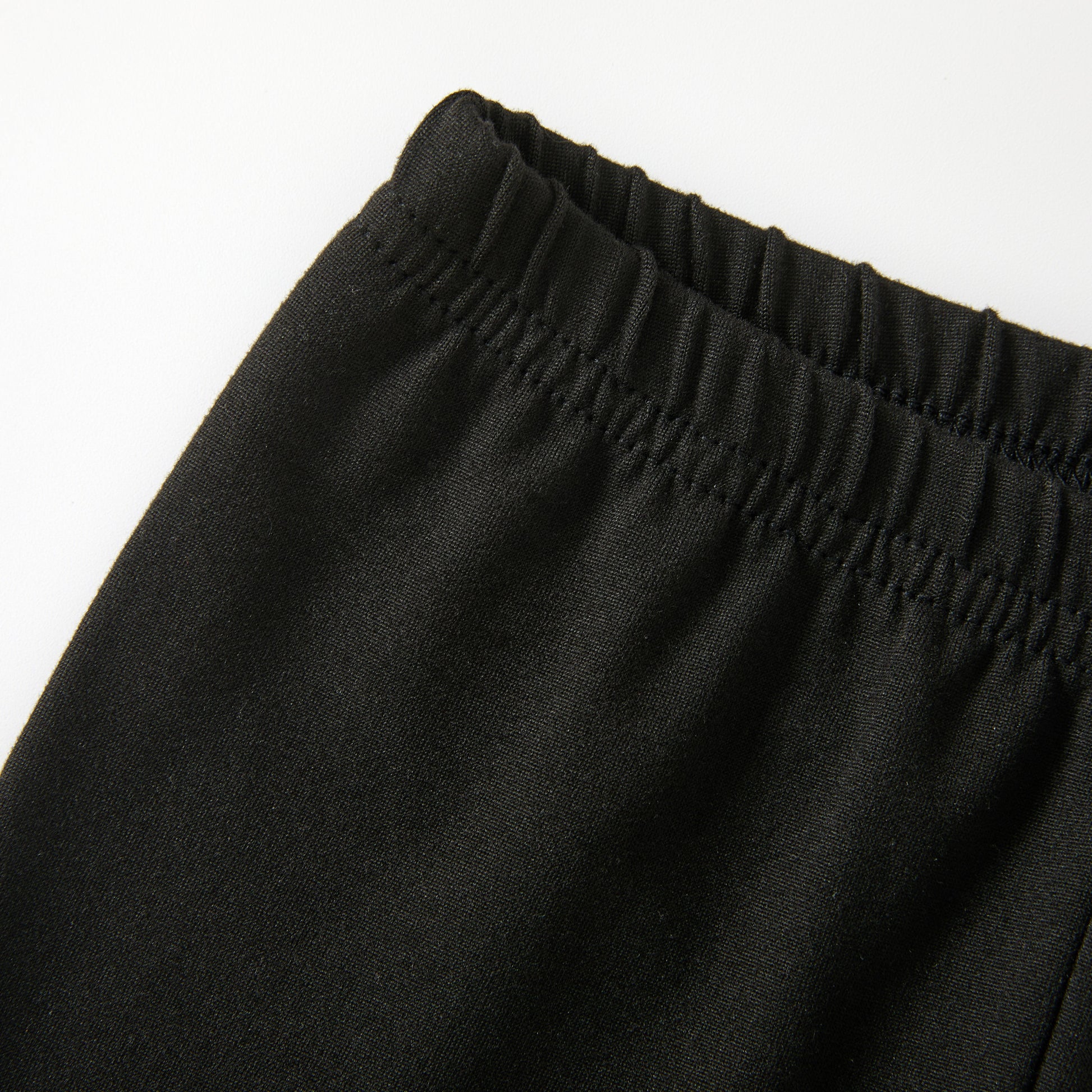 Close-up of the elastic waistband on the pants against a plain white background.