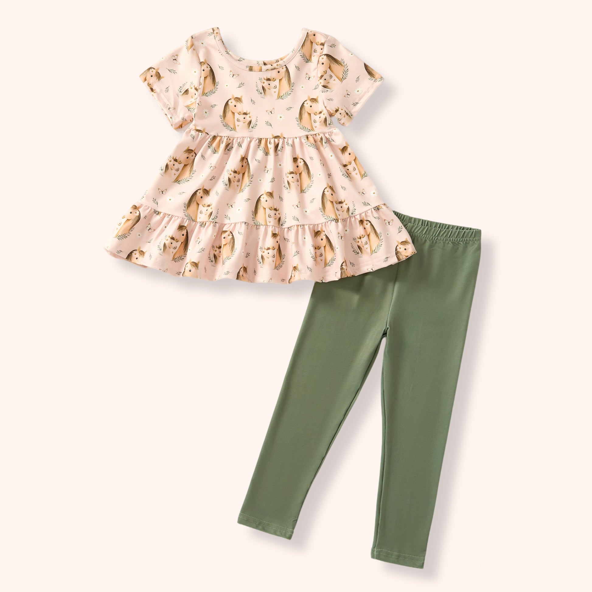 Children's outfit with a horse patterned top and green leggings on a white background