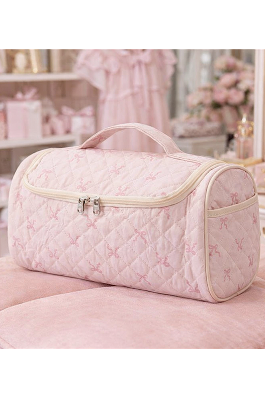 Pink quilted toiletry bag with butterfly pattern on a pink surface
