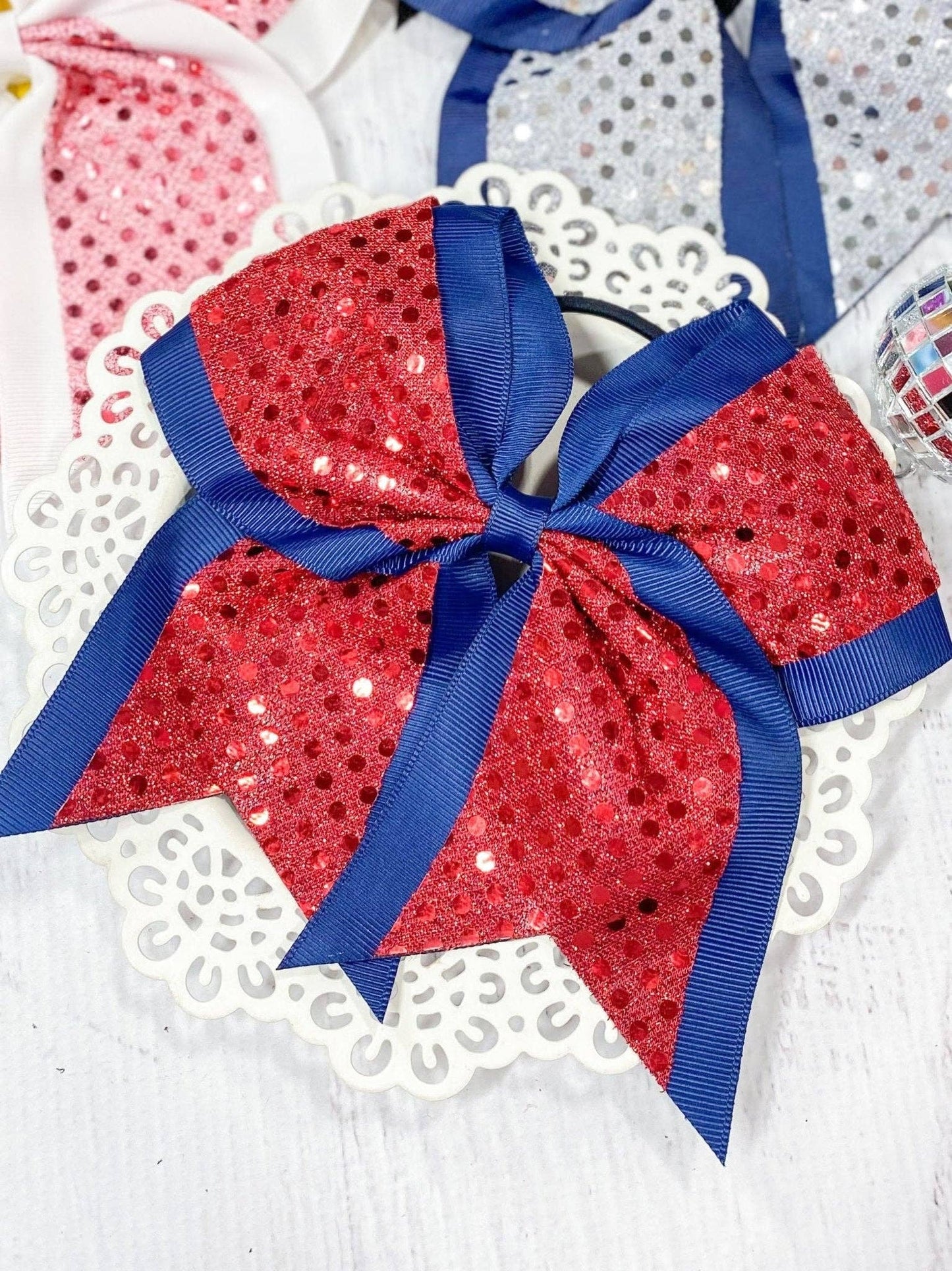 Red sequin hair bow with blue ribbon on a white background