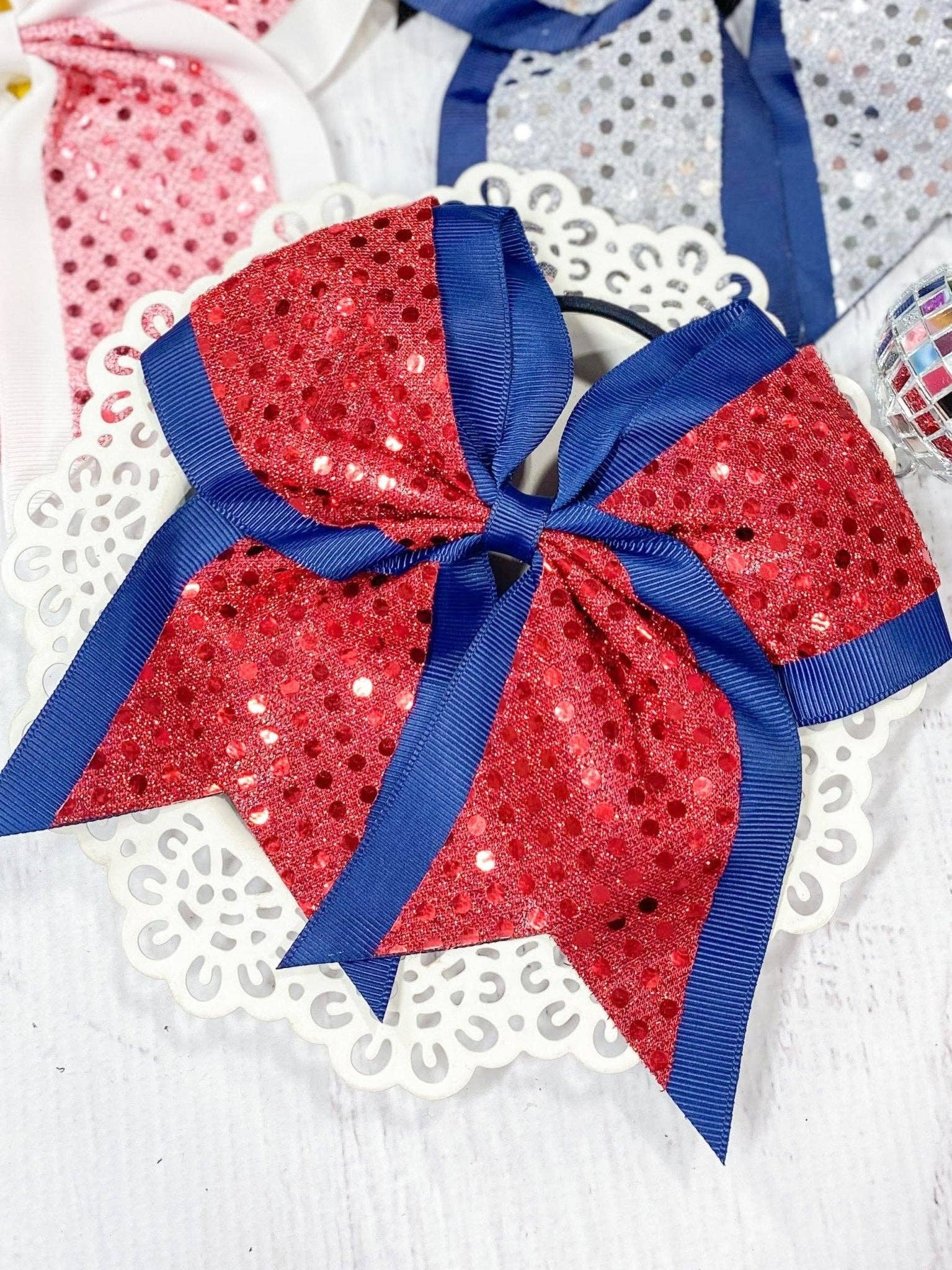 Red sequin hair bow with blue ribbon on a white background