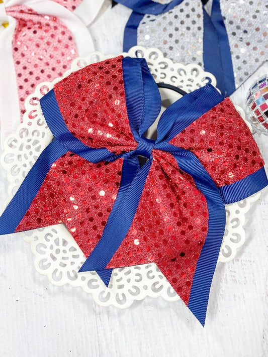 Red sequin hair bow with blue ribbon on a white background