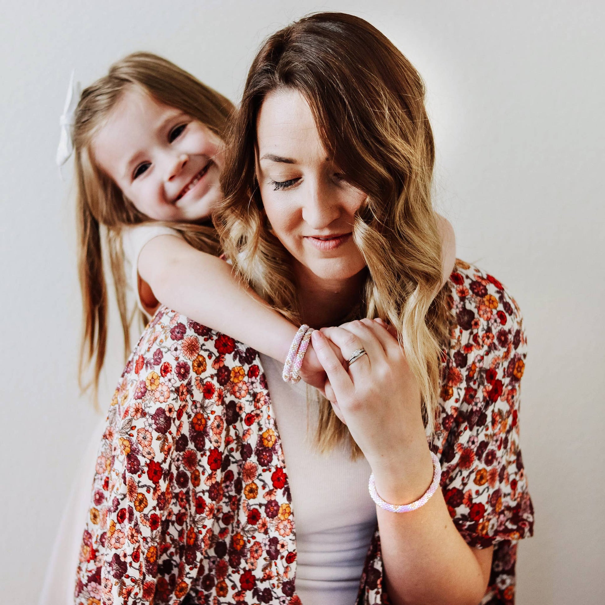 Woman and young girl wearing floral jackets against a plain background
