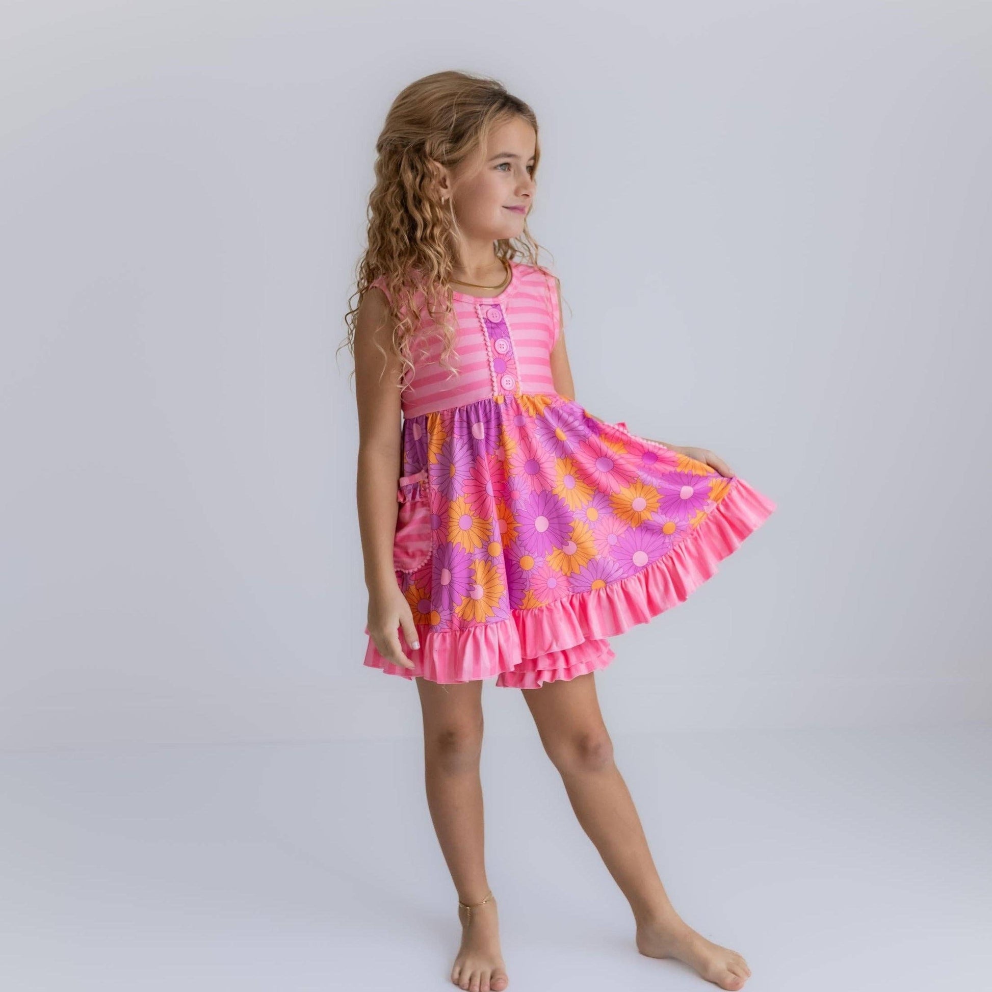 Young girl wearing a colorful dress with a pink and orange pattern on a white background