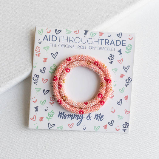 Pink beaded bracelet on Aid Through Trade packaging with 'Mommy & Me' text.