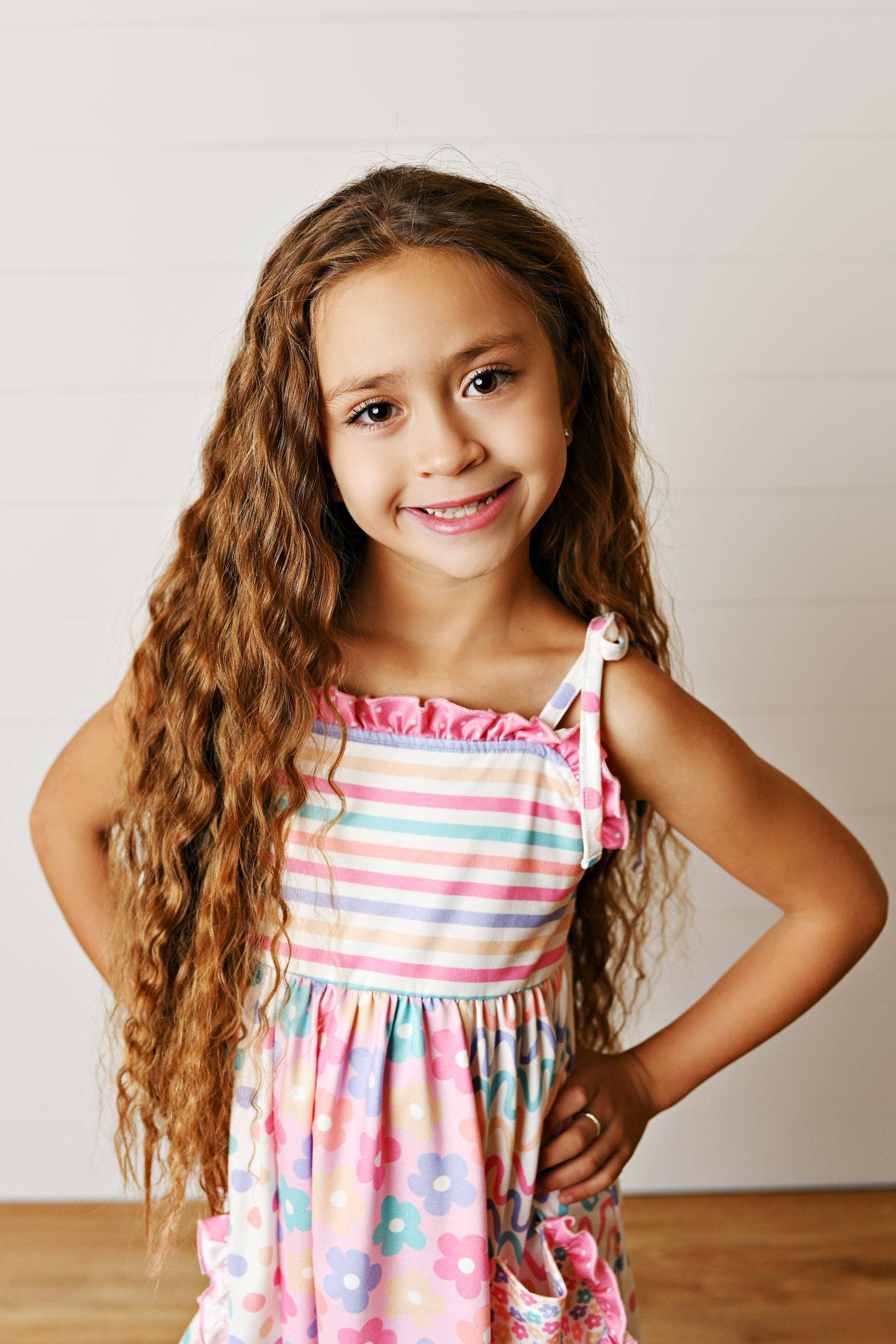 Young girl wearing a colorful striped dress with a plain background