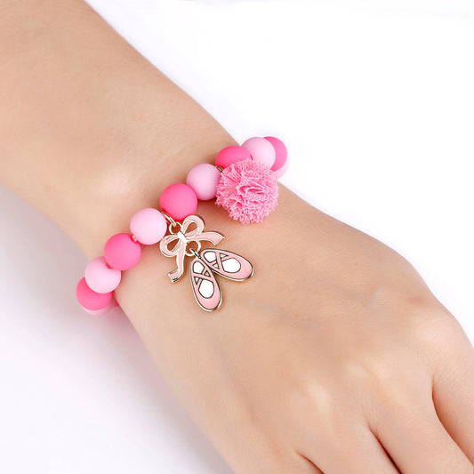 Pink beaded bracelet with ballet slipper and bow charm on a wrist against a white background